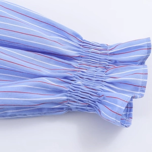 Detail der gesmokten elastischen Manschette mit roten Streifen auf blau gestreiftem Hemd