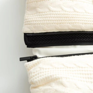 Detail view of cream cable knit fabric with black zipper and mesh lining textures