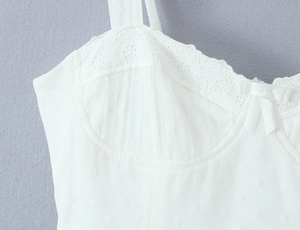Close-up of white mesh dress featuring delicate floral lace and a small bow detail