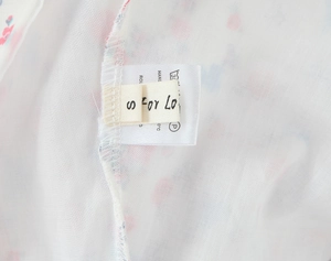 Detailed close-up showing quality stitching and size S care label on floral summer dress