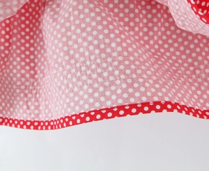 Detailed view of red polka dot skirt fabric with clean double-stitched hem finish