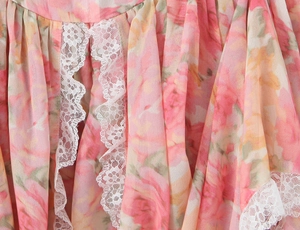 Détail du tissu floral rose avec une bordure en dentelle blanche délicate sur l'ourlet