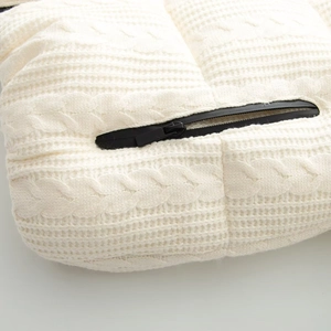 Detail of white cable knit texture and black zipper on winter ski jacket fabric