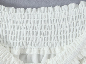 Detailed view of white smocking embroidery and elastic shirring on summer top fabric