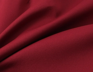 Close-up detail of burgundy woven fabric showing refined texture and elegant drape