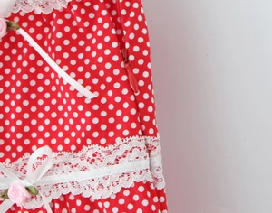 Detailed macro view of red polka dot fabric with white lace trim and pink floral bow
