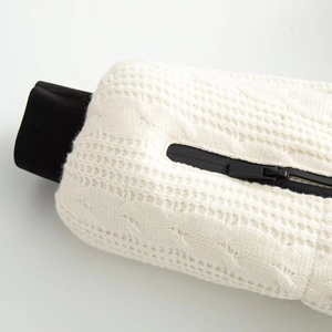 Detailed close-up of white cable knit fabric with black ribbed cuffs and zipper