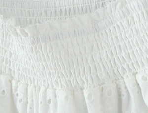 Detail of white cotton set featuring smocking elastic texture and eyelet embroidery lace