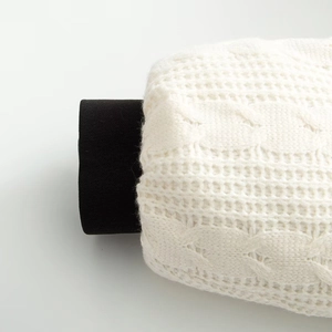 Macro detail of white chunky cable knit texture with contrasting black inner lining