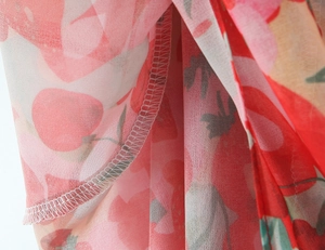 Detailed view of floral chiffon fabric featuring red blossoms and fine hem stitching