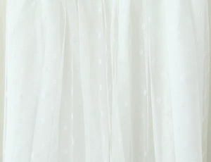 Detailed close-up of white mesh fabric featuring delicate polka dots and pleated texture