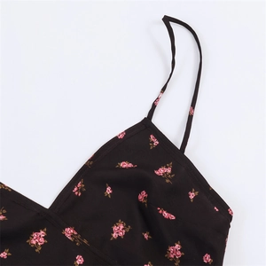 Détail d'une robe noire à fleurs roses avec fines bretelles et décolleté en V profond
