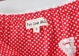 Macro detail of red polka dot skirt waist with elastic shirring and white lace trim