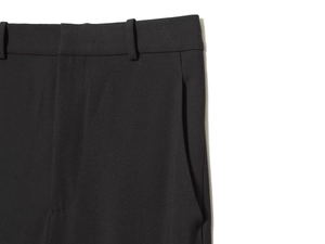 Detail of black dress pants featuring waistline, belt loops, and side pockets in woven fabric