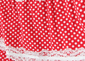 Close-up of red polka dot fabric with intricate double-layered white lace trim detailing