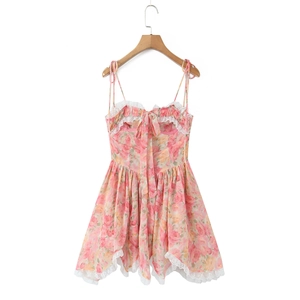 Détails d'une robe fleurie avec des nœuds roses et une bordure en dentelle blanche