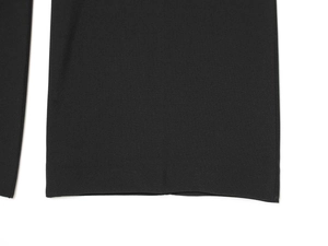 Detailed close-up of premium black fabric texture and neat hem stitching of trousers
