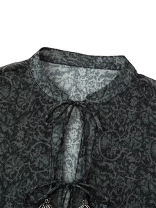 Détails du col mandarin et des pompons métalliques sur chemisier gris à imprimé
