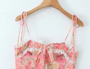 Détail de robe fleurie rose avec bordure dentelle, nœud et fines bretelles réglables
