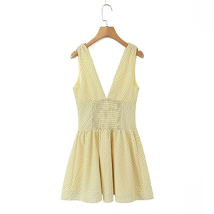 Detail of a bright yellow polka dot summer dress with deep V-neck and elastic waist