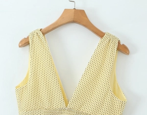 Detailed view of the yellow V-neck dress featuring black polka dots and pleated waist