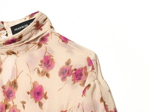 Detail of high neck design and pearl buttons on a floral sheer blouse with rose patterns