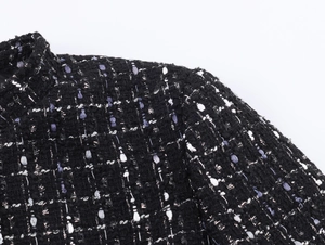 Detail of black tweed jacket featuring purple metallic threads and premium woven texture