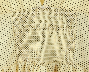 Detail of yellow polka dot dress showing smocked elastic waist and V-neckline texture