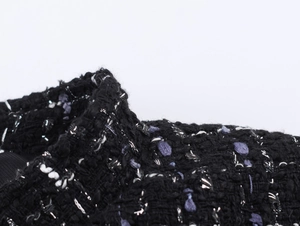 Macro shot of black tweed fabric with purple and silver metallic thread texture