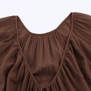 Detail of V-neckline on brown pleated mesh mini dress with adjustable drawstrings
