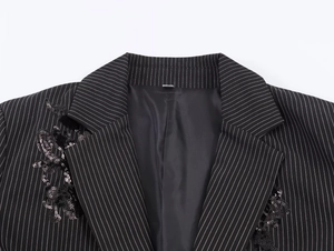Detail of sequin embroidery and white pinstripes on a black blazer with notch lapels