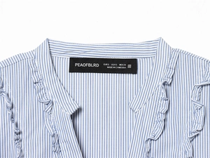 Close-up of V-neckline with ruffle trim on a blue and white striped cotton shirt