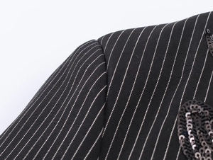 Macro shot of black pinstripe fabric with detailed black sequin embroidery on jacket