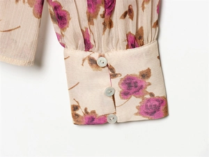 Close-up of floral long sleeve cuff with three white buttons on a cream blouse