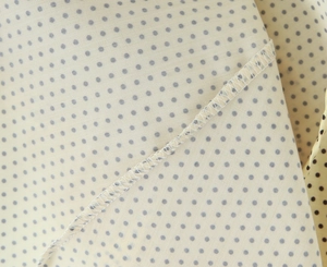 Detailed macro view showing white overlock stitching on a yellow fabric with grey polka dots
