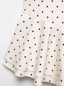 Close-up of cream white polka dot dress featuring double-layered wavy hem and ruffles