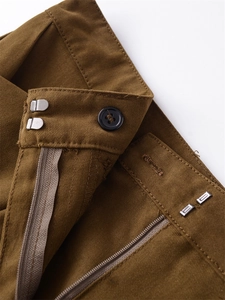 Macro shot of brown twill trousers featuring resin button and metal hook waist closure