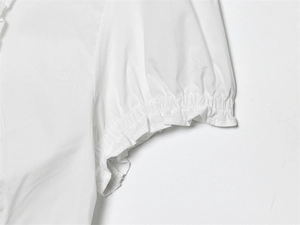 Detail of white cotton blouse sleeve featuring elastic smocked cuffs and ruffled edge