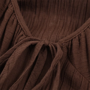 Detail view of V-neckline with tie-up bow on brown pleated sheer fabric dress