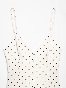 Detail of V-neck spaghetti strap dress with black polka dots on ivory fabric