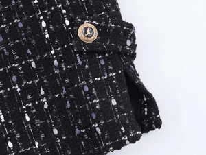 Macro detail of tweed fabric texture and a gold embossed lion head decorative button