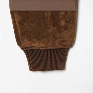 Gros plan d'une veste en daim marron foncé montrant les poignets en tricot et la texture