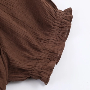 Detailed view of dark brown elastic smocked fabric with delicate pleated texture