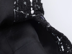 Macro shot of tweed fabric texture with metallic threads and black twill lining detail