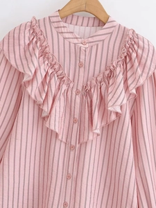 Detailed view of pink striped shirt with ruffle layers and stand collar on wooden hanger