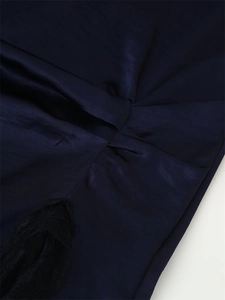 Close-up of ruched dark blue satin fabric and delicate black lace trim on dress hem