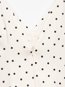 Close-up of V-neckline with invisible zipper on cream white polka dot dress