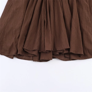 Detail of brown pleated fabric with fine vertical pleats on the dress skirt hem