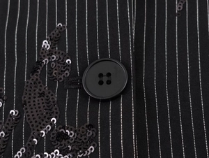 Detail of black pinstripe fabric featuring hand-sewn sequins and a classic four-hole button
