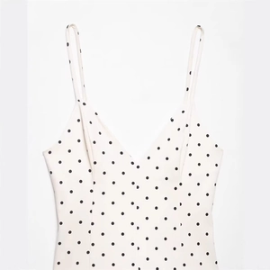 Detailed view of the fine spaghetti straps and V-neckline of a polka dot summer dress